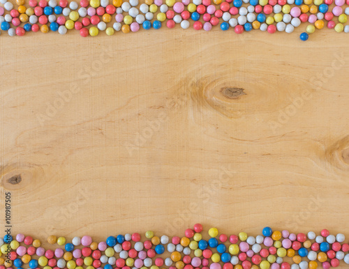 Multicolored round sugar candies on natural wood background