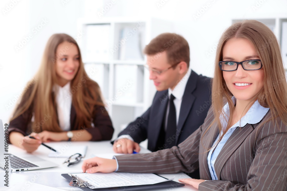 A group of business people at a meeting on the background of office. Focus on a beautiful brunette A group of business people at a meeting on the background of office. Focus on a beautiful brunette