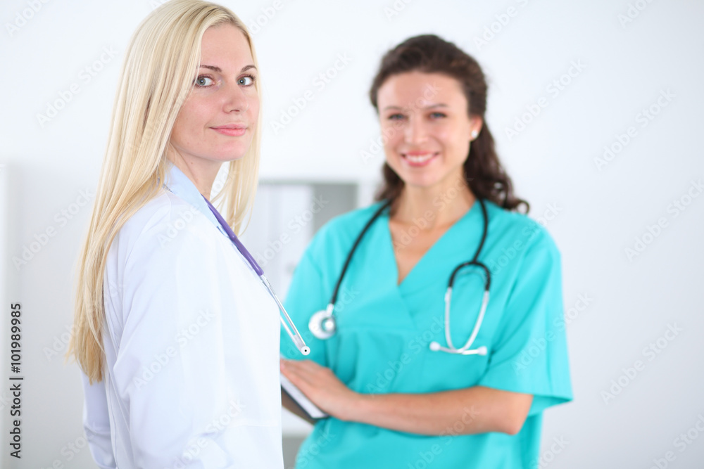 Two confident friendly female doctors sitting at the table and listen to the patient's history . Medical and health care concept Two confident friendly female doctors sitting at the table and listen to the patient's history . Medical and health care concept