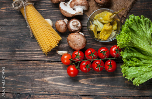 Pasta, tomatoes, salad, pepper, mushrooms and book of recipes on wooden table background