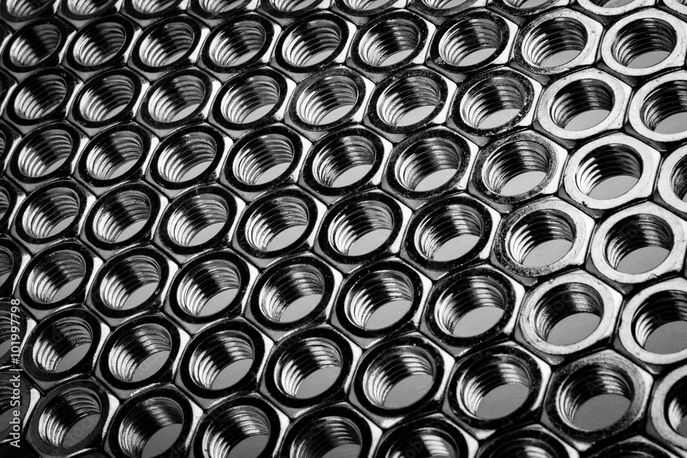 Nut screws tightly stacked next to each other on a flat surface. Nut background isolated on white.