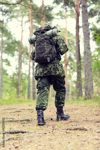 young soldier with backpack in forest