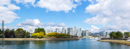 panoramic view of the buildings of vancouver city skyline behind a marina during a sunny day in british columbia in canada