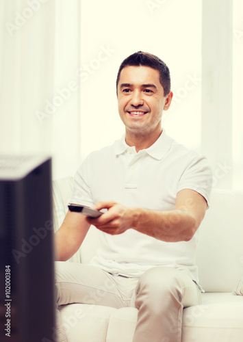 smiling man with remote control watching tv