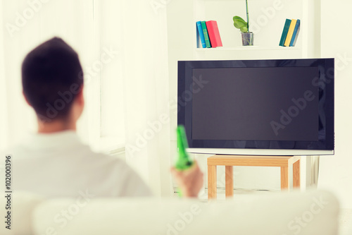 man watching tv and drinking beer at home