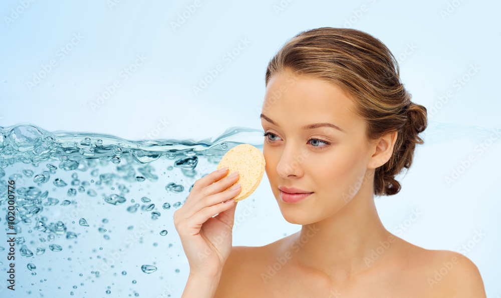 young woman cleaning face with exfoliating sponge young woman cleaning face with exfoliating sponge