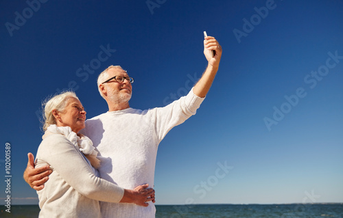 seniors with smartphone taking selfie on beach