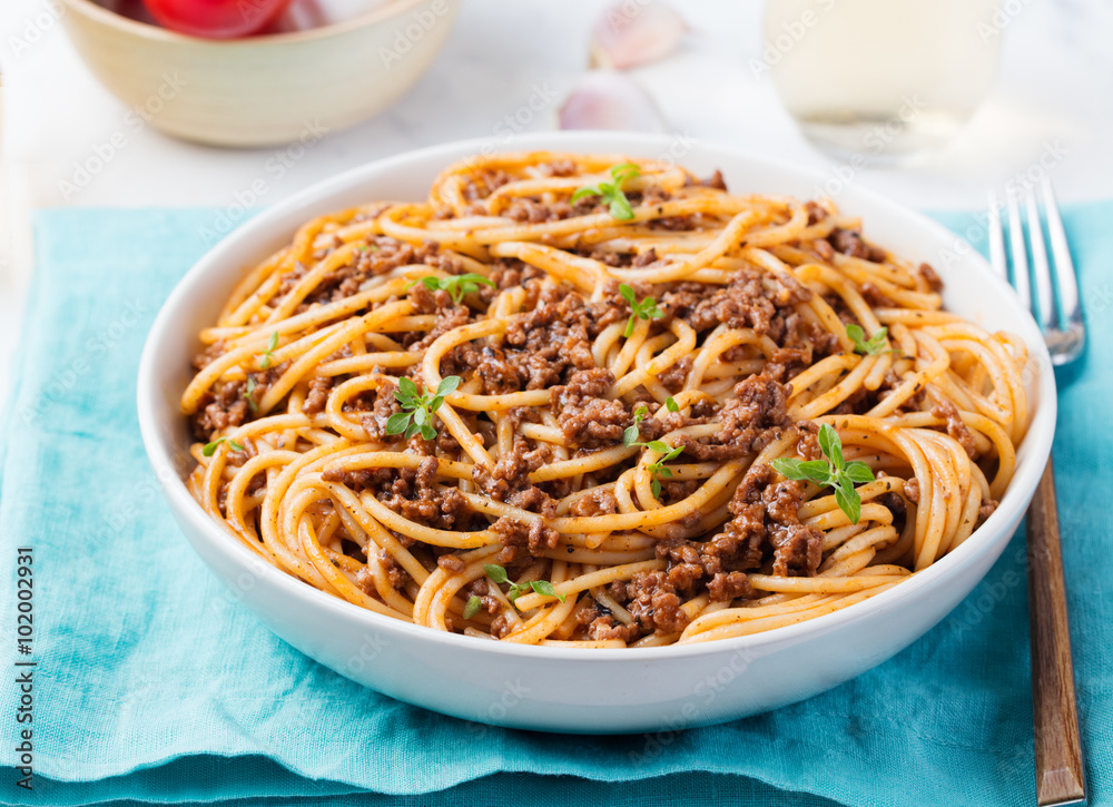 Spaghetti bolognese with cheese and basil on a plate Italian ingredients background