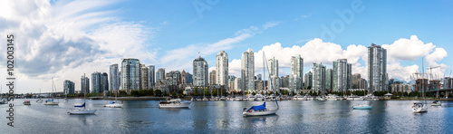 panoramic view of the buildings of vancouver city skyline behind a marina during a sunny day in british columbia in canada