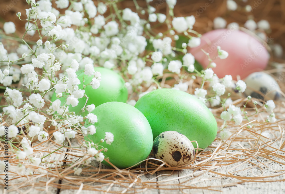 Green easter eggs on old wooden background with dry straws and w