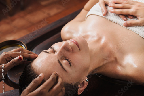 Schilderij op canvas Ayurvedic face massage with oil on the wooden table