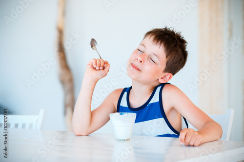 Smiling little boy eating delicious yogurt