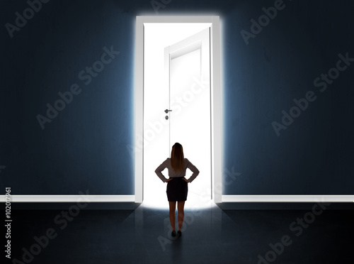 Business woman looking at big bright opened door