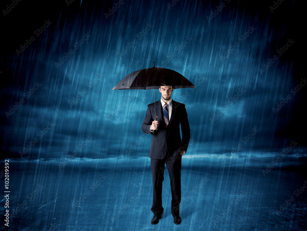 Business man standing in rain with an umbrella Business man standing in rain with an umbrella