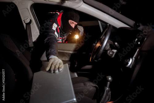 Robber breaking a car's to steal a lap top