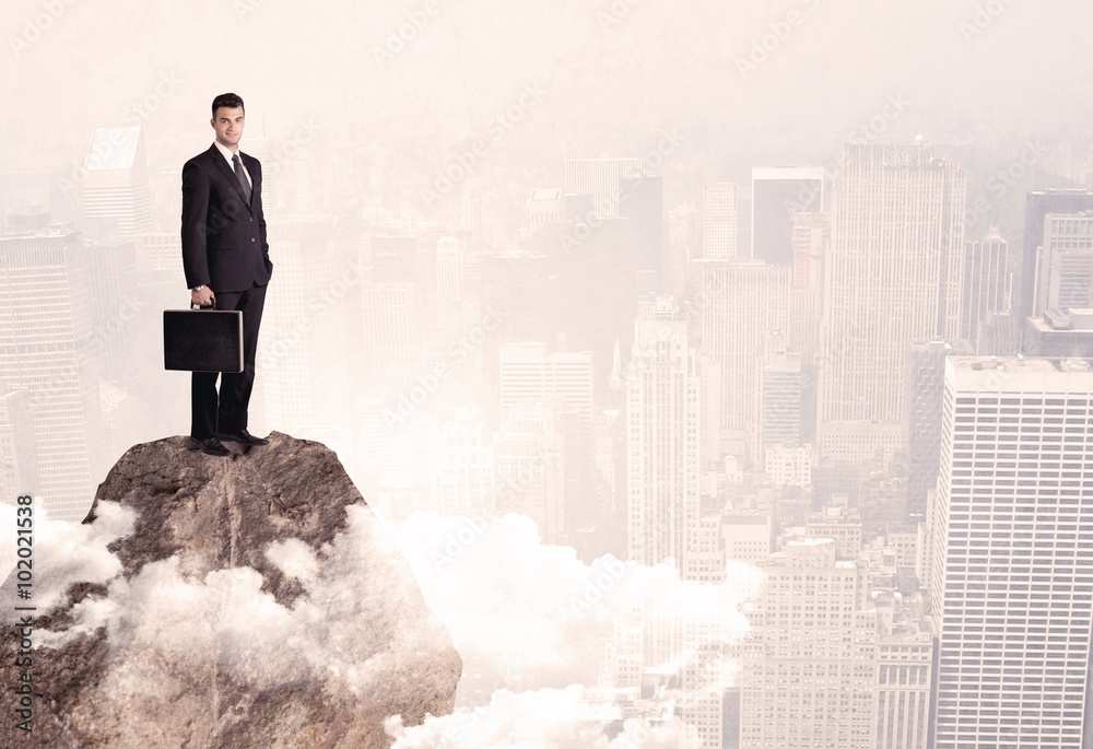 Happy businessman standing on stone top Happy businessman standing on stone top