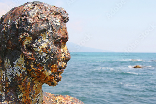 Rusty old head of the statue on the beach. Illustration to an ar