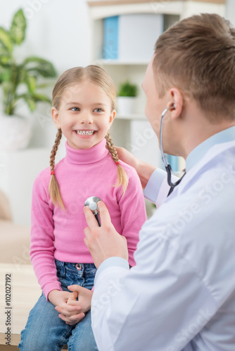 Professional pediatrician examining little girl 