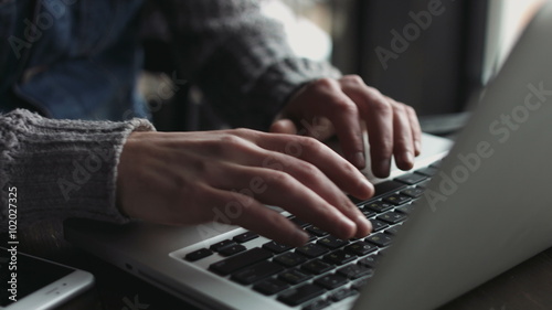 Close-up of male caucasian hands typing on a keyboard. Man using  laptop indoors.