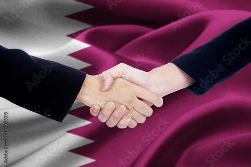 Agreement handshake with flag of Qatar