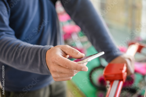 Closeup on person holding mobile phone in hand during shopping. Cart on background of store