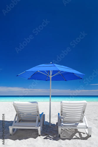 Caribbean beach with blue sun umbrellas and white beds © photopixel