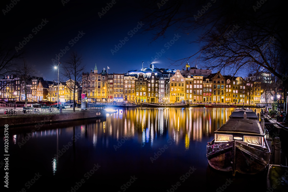 Living by the water. Old town Amsterdam canal houses in a blue, bright winter evening.