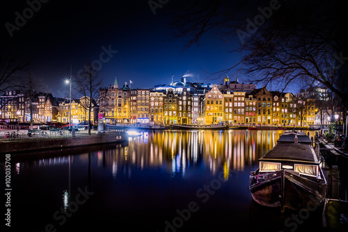 Living by the water. Old town Amsterdam canal houses in a blue, bright winter evening. © storm_nl