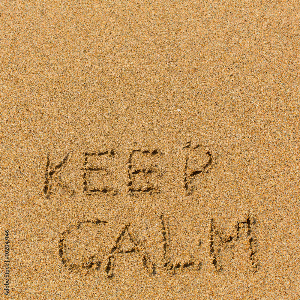 Fototapeta premium Keep calm - text written on sandy beach. Background, texture of the sand..