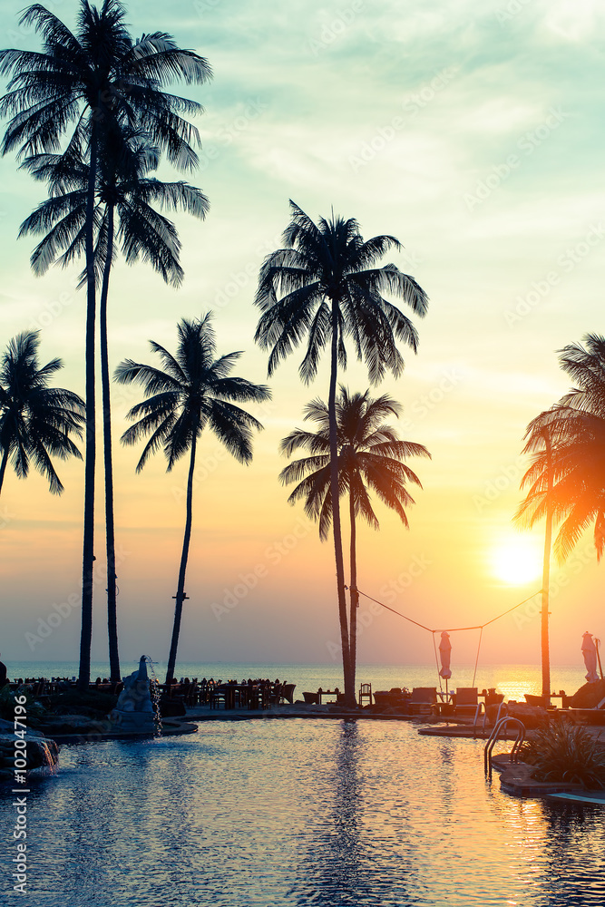 Tropical beach at amazing sunset, exotic paradise landscape with silhouettes of palm trees..