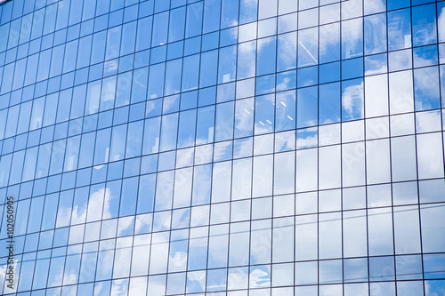Window of a big office building. Blue sky and fluffy white clouds reflected in the windows of modern skyscraper. 