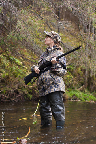 woman hunter on small river in the forest