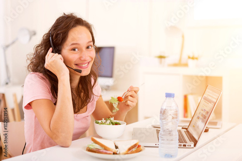 Young attractive student eating while working