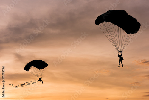 Silhouette of parachute and airplane on sunset background