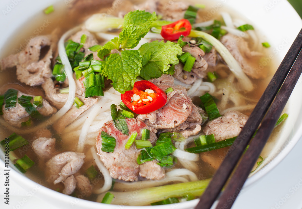 Traditional Vietnamese beef soup pho on a wooden background Traditional Vietnamese beef soup pho on a wooden background