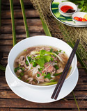 Traditional Vietnamese beef soup pho on a wooden background