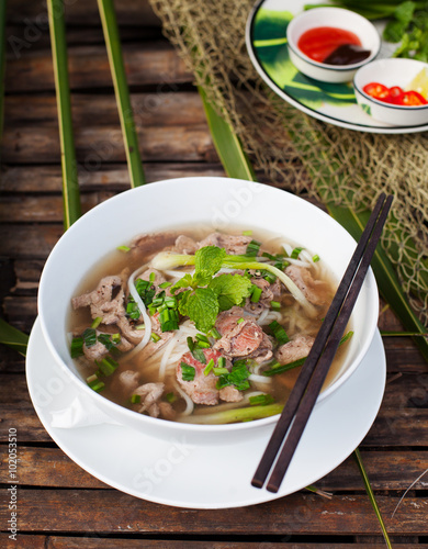 Traditional Vietnamese beef soup pho on a wooden background photo