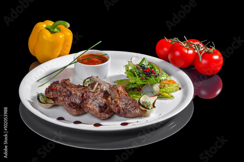 Жареное мясо с овощами на черном фоне