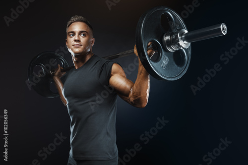 Muscular man training squats with barbells over head