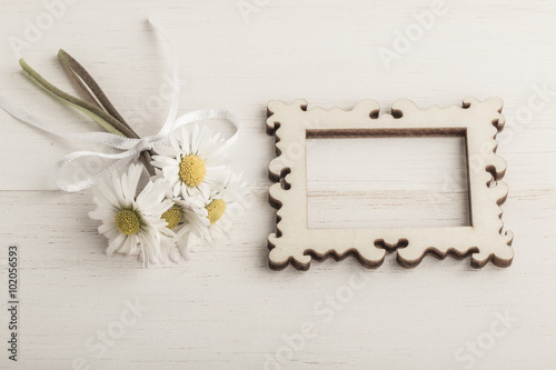 daisy flowers and an empty frame on wooden background