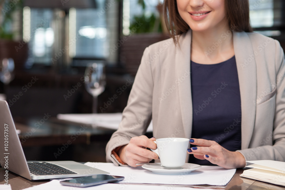 Cheerful female worker is enjoying hot drink Cheerful female worker is enjoying hot drink