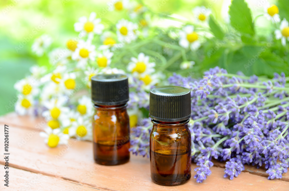 essential oils with herbal flowers on wooden table essential oils with herbal flowers on wooden table