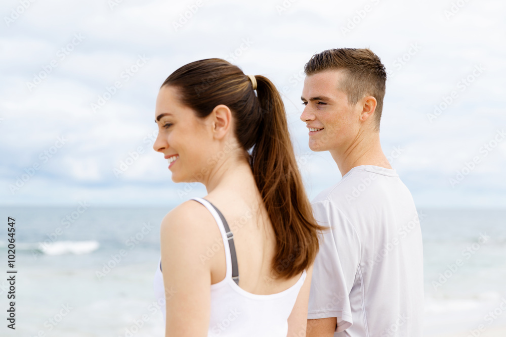 Young couple looking thoughtful while standing next to each other on beach Young couple looking thoughtful while standing next to each other on beach