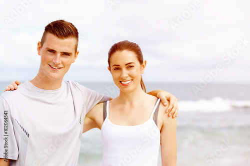 Young couple looking at camera while standing on beach