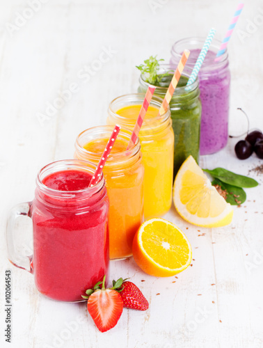 Smoothies, juices, beverages, drinks variety with fresh fruits and berries on a white wooden background.