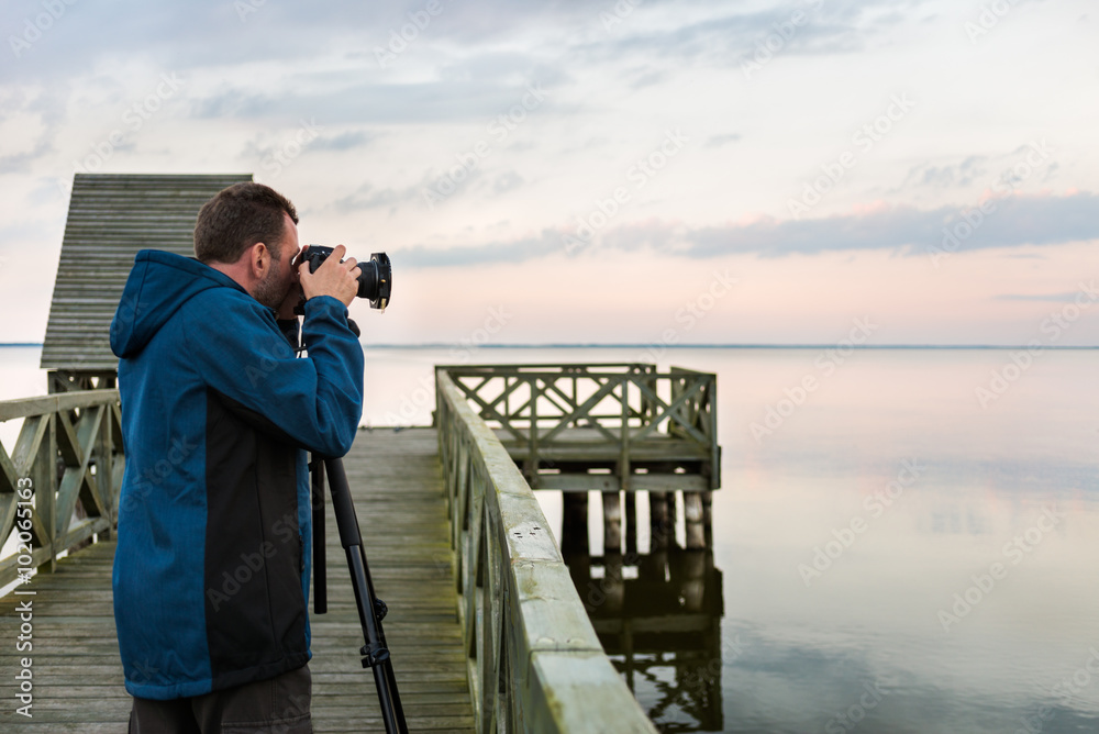 Obraz premium Nature photographer taking photos of the lake at sunset