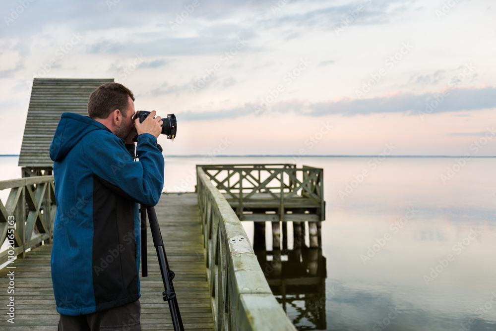 Nature photographer taking photos of the lake at sunset