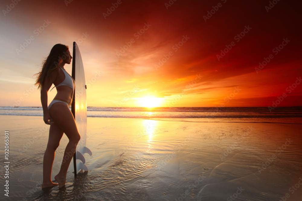 Surfer girl on beach at sunset
