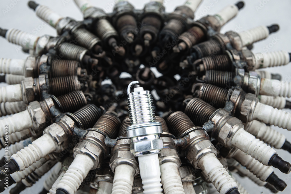 Spark plug on a background of used spark plugs arranged in a circle at a shallow depth of field Spark plug on a background of used spark plugs arranged in a circle at a shallow depth of field