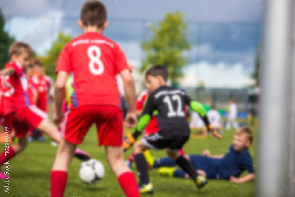 Blurred sport soccer football background. Young boys playing football match. children's soccer match. Red against black team. Blurred sport soccer football background. Young boys playing football match. children's soccer match. Red against black team.